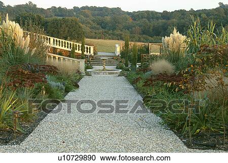 Stock Image - Gravel path through herbaceous borders with cortaderia in large country garden in summer. Fotosearch