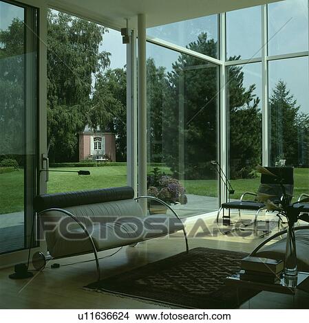Grey leather and chrome sofa in modern living room with large windows View Large Photo Image Picture - Grey leather and chrome sofa in modern living room with large windows. Fotosearch
