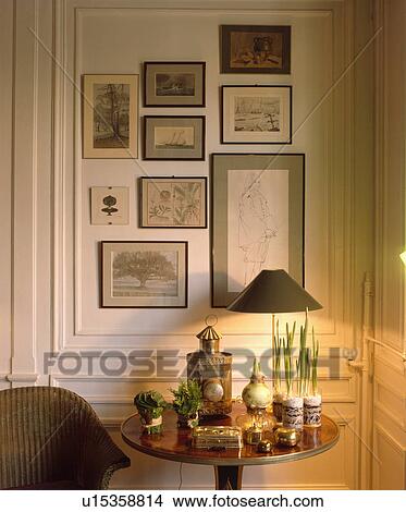 Group of pictures on wall above lighted lamp on table with collection of silver boxes View Large Photo Image Picture - Group of pictures on wall above lighted lamp on table with collection of silver boxes. Fotosearch