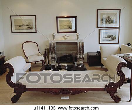 Stock Image - Group of pictures on wall in traditional living room with cream chaiselongue. Fotosearch