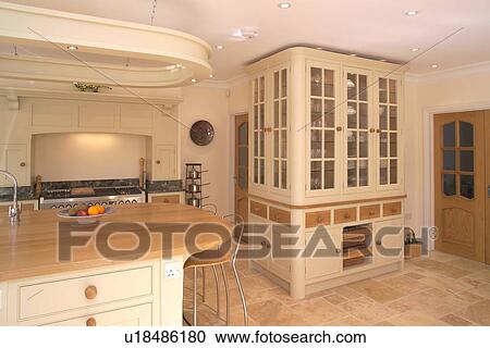Island unit with wood worktop and breakfast bar in modern cream kitchen with large fitted central cupboard View Large Photo Image Stock Image - Island unit with wood worktop and breakfast bar in modern cream kitchen with large fitted central cupboard. Fotosearch