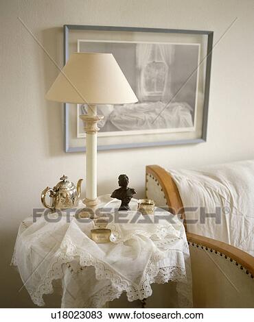 Stock Image - Lamp on small table with lace cloth. Fotosearch