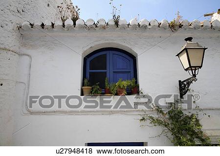 Lamp on wall beside window with blue shutters in traditional Spanish house View Large Photo Image Stock Photo - Lamp on wall beside window with blue shutters in traditional Spanish house. Fotosearch