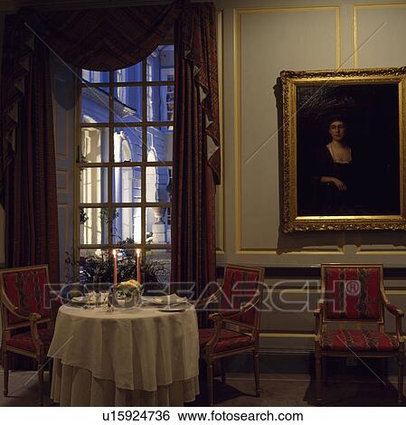 Large picture on grey panelled wall beside tall window in dining room with white cloth on small white table View Large Photo Image Stock Photograph - Large picture on grey panelled wall beside tall window in dining room with white cloth on small white table. Fotosearch