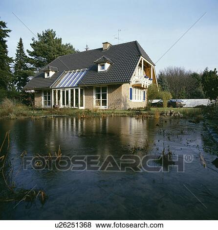Stock Photo - Large pond in front of modern house in the country. Fotosearch