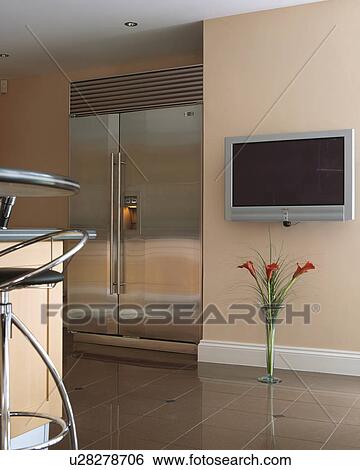 Large stainless steel American-style fridge freezer beside flatscreen television on wall of modern kitchen View Large Photo Image Stock Photograph - Large stainless steel American-style fridge freezer beside flatscreen television on wall of modern kitchen. Fotosearch