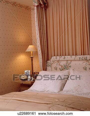 Lighted lamp on table beside bed with peach silk drapes on canopy above bed with white lace cushions View Large Photo Image Stock Image - Lighted lamp on table beside bed with peach silk drapes on canopy above bed with white lace cushions. Fotosearch