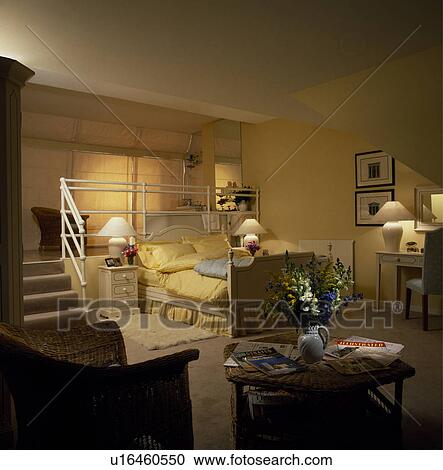 Lighted lamps in openplan yellow living and bedroom with yellow quilt and pillows on bed View Large Photo Image Stock Image - Lighted lamps in openplan yellow living and bedroom with yellow quilt and pillows on bed. Fotosearch