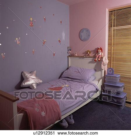 Stock Image - Mauve and pink walls above white bed with mauve bedlinen in economy-style child's bedroom with plastic storage boxes. Fotosearch