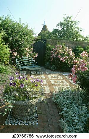 Metal bench and table on brick and pebble patio in country garden in summer View Large Photo Image Stock Photograph - Metal bench and table on brick and pebble patio in country garden in summer. Fotosearch