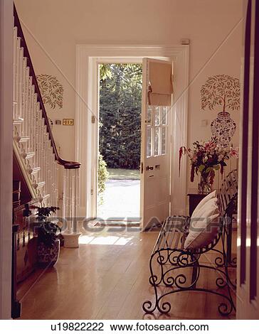 Metal bench and wooden flooring in white country hall with stencilled trees on either side of open front door View Large Photo Image Stock Image - Metal bench and wooden flooring in white country hall with stencilled trees on either side of open front door. Fotosearch