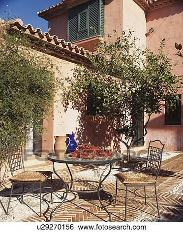 Metal table and chairs on patio in front of Spanish villa View Large Photo Image Stock Photograph - Metal table and chairs on patio in front of Spanish villa. Fotosearch