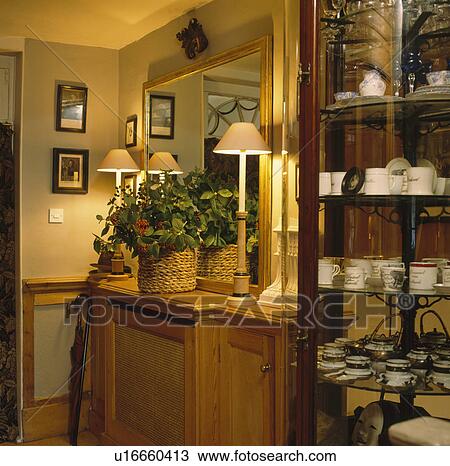 Mirror Above Lighted Lamps On Either Side Of Houseplant In Basket