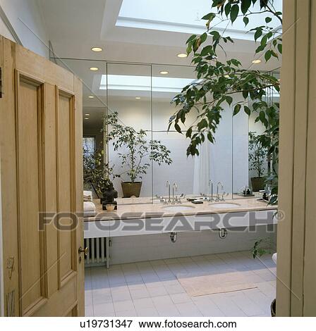 Stock Photo - Mirrored wall above vanity unit with double basins in modern white loft bathroom with white floor tiles. Fotosearch