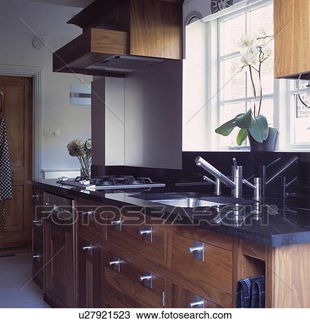 Modern kitchen with wooden fitted cupboardsand chrome mixer tap with white sink underset in black granite worktop View Large Photo Image Stock Image - Modern kitchen with wooden fitted cupboardsand chrome mixer tap with white sink underset in black granite worktop. Fotosearch
