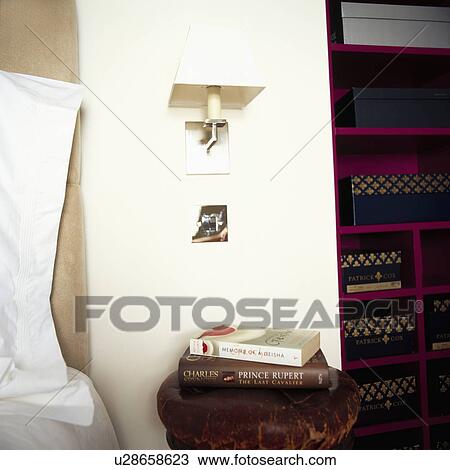 Modern wall light above books on antique stool in modern bedroom View Large Photo Image Stock Image - Modern wall light above books on antique stool in modern bedroom. Fotosearch