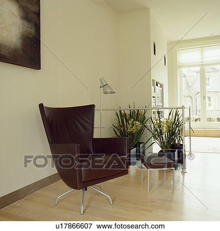 Stock Photo - Montis black leather swivel armchair on maple wood flooring in modern city livingroom. Fotosearch