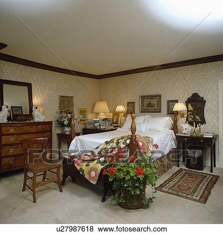 Neutral patterned wallpaper in traditional bedroom with lighted lamps and large basket of red geraniums View Large Photo Image Stock Photo - Neutral patterned wallpaper in traditional bedroom with lighted lamps and large basket of red geraniums. Fotosearch