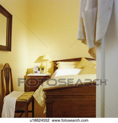 Open doorway to pastel yellow bedroom with mahogany bed and antique chair View Large Photo Image Stock Image - Open doorway to pastel yellow bedroom with mahogany bed and antique chair. Fotosearch