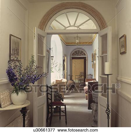 Open half-glazed doors below Georgian fanlight in hall with view of living room View Large Photo Image Stock Photo - Open half-glazed doors below Georgian fanlight in hall with view of living room. Fotosearch
