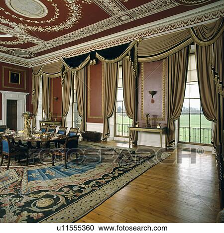 Ornate Ceiling And Swagged Curtains At Tall Windows In Dining Room