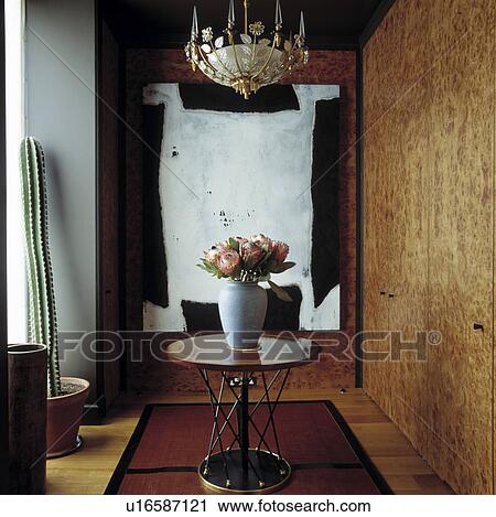 Ornate light above flowers on circular modern table in hall with paint effect wall and large black+white abstract picture View Large Photo Image Stock Image - Ornate light above flowers on circular modern table in hall with paint effect wall and large black+white abstract picture. Fotosearch