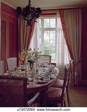 Oval table set for lunch with white china in pink dining room with white sheers and pink-bordered cream curtains View Large Photo Image Picture - Oval table set for lunch with white china in pink dining room with white sheers and pink-bordered cream curtains. Fotosearch