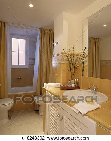 Ovan white basin set into vanity unit with pale yellow tiled top in modern white bathroom with yellow curtains beside bath View Large Photo Image Stock Image - Ovan white basin set into vanity unit with pale yellow tiled top in modern white bathroom with yellow curtains beside bath. Fotosearch