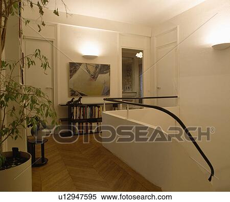 Parquet flooring on modern white landing with uplighter above picture and metal handrail on low bannister wall View Large Photo Image Stock Photography - Parquet flooring on modern white landing with uplighter above picture and metal handrail on low bannister wall. Fotosearch