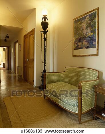 Pastel green upholstered sofa below picture and lighted lamp on plinth in hall with large sisal rug View Large Photo Image Stock Image - Pastel green upholstered sofa below picture and lighted lamp on plinth in hall with large sisal rug. Fotosearch