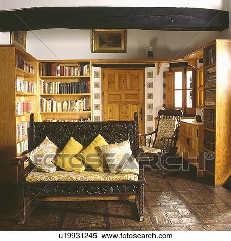 Patterned and plain yellow cushions on carved wooden settle in Spanish country living room with tiled floor View Large Photo Image Stock Photography - Patterned and plain yellow cushions on carved wooden settle in Spanish country living room with tiled floor. Fotosearch