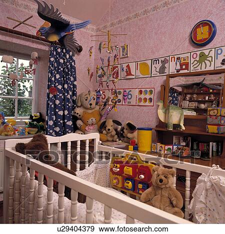 Patterned blue curtains and paper parrot in cluttered nursery bedroom with white cot and paper freize on pink wallpaper View Large Photo Image Stock Photo - Patterned blue curtains and paper parrot in cluttered nursery bedroom with white cot and paper freize on pink wallpaper. Fotosearch