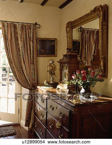 Patterned curtains and antique chest-of-drawers in country living room View Large Photo Image Picture - Patterned curtains and antique chest-of-drawers in country living room. Fotosearch