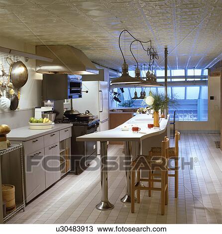 Pendant lamps above long breakfast bar in loft conversion kitchen with textured ceiling and tiled floor View Large Photo Image Stock Image - Pendant lamps above long breakfast bar in loft conversion kitchen with textured ceiling and tiled floor. Fotosearch
