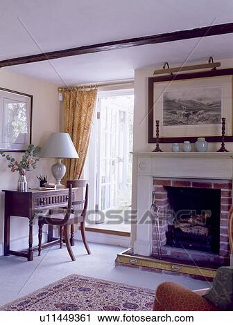 Picture above fireplace in country livingroom with antique desk and chair beside open French windows View Large Photo Image Stock Image - Picture above fireplace in country livingroom with antique desk and chair beside open French windows. Fotosearch