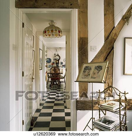 Picture on music stand in white beamed cottage hall with view through doorway of black+white checked flooring View Large Photo Image Stock Photo - Picture on music stand in white beamed cottage hall with view through doorway of black+white checked flooring. Fotosearch