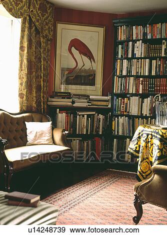 Stock Photo - Picture on wall to ceiling bookshelves in country living room. Fotosearch