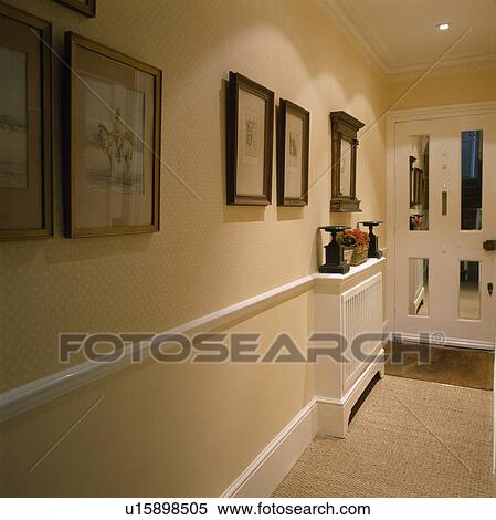 Stock Photography - Pictures above dado rail in neutral hall with spotted wallpaper and sisal carpet. Fotosearch