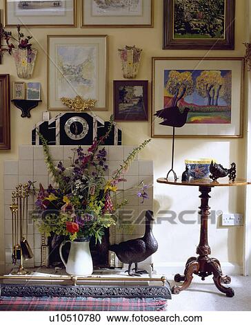 Stock Image - Pictures above fireplace with fresh flower arrangement. Fotosearch
