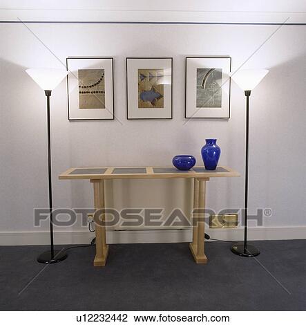 Pictures above pale wood modern console table in modern white hall with uplighter lamps View Large Photo Image Stock Image - Pictures above pale wood modern console table in modern white hall with uplighter lamps. Fotosearch