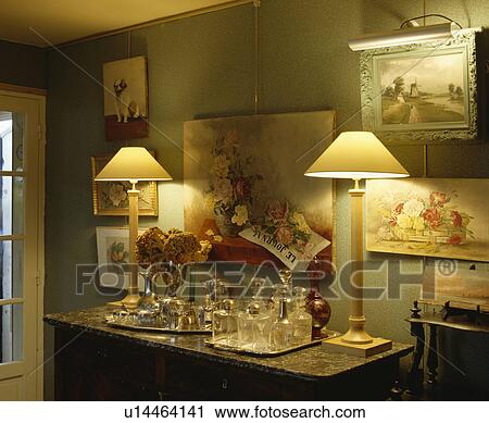 Pictures on green wall above lighted lamps and antique glass decanters on marble-topped table View Large Photo Image Stock Image - Pictures on green wall above lighted lamps and antique glass decanters on marble-topped table. Fotosearch