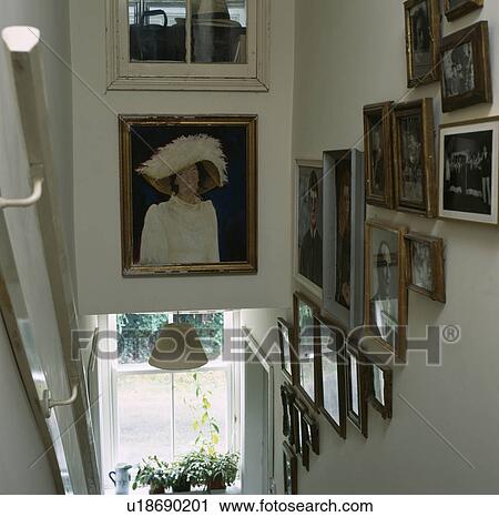 Stock Image - Pictures on the walls above narrow staircase. Fotosearch