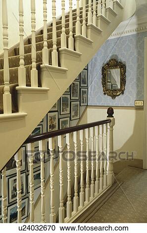 Stock Image - Pictures on wall of staircase with cream bannisters . Fotosearch