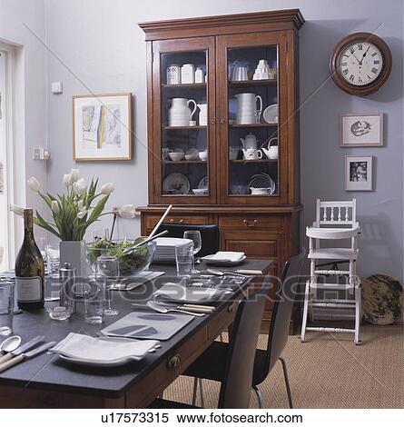 Place settings on slate-topped table in grey dining room with clock above white highchair and tall dresser View Large Photo Image Stock Photography - Place settings on slate-topped table in grey dining room with clock above white highchair and tall dresser. Fotosearch