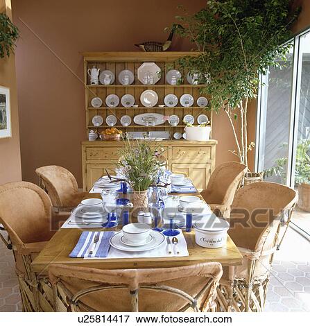 Place settings on table with leather and chestnut-wood chairs in terracotta dining room with pine dresser View Large Photo Image Stock Photo - Place settings on table with leather and chestnut-wood chairs in terracotta dining room with pine dresser . Fotosearch