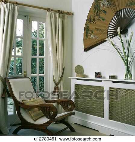 Planter S Chair In Front Of French Windows With Cream Curtains In Living Room With Large Chinese Fan On Wall Above Radiator With Wood And Mesh Cover Stock Image U12780461 Fotosearch,How To Take Care Of Wood Floors