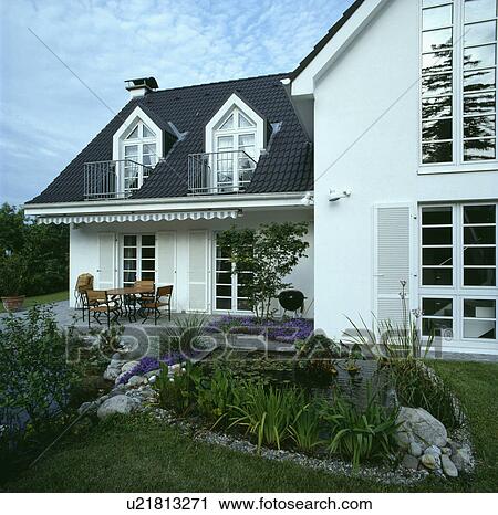 Stock Image - Pond in garden in front of traditional white country house. Fotosearch