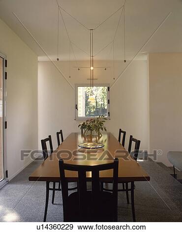 Rectangular table below suspended lighting in modern white dining room View Large Photo Image Stock Photo - Rectangular table below suspended lighting in modern white dining room. Fotosearch
