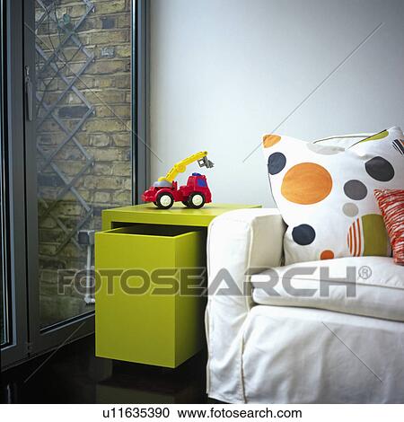 Red toy truck on lime green table with pull out storage drawer beside spotted cushion on white sofa in modern living room View Large Photo Image Stock Image - Red toy truck on lime green table with pull out storage drawer beside spotted cushion on white sofa in modern living room. Fotosearch