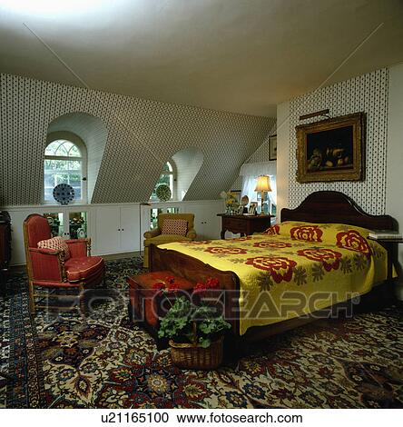 Red+yellow patchwork quilt on bed in large attic bedroom with patterned carpet and red armchair View Large Photo Image Stock Image - Red+yellow patchwork quilt on bed in large attic bedroom with patterned carpet and red armchair. Fotosearch